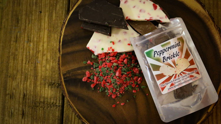 Small bag of Peppermint Brickle open on wooden serving tray with red and green peppermint bits