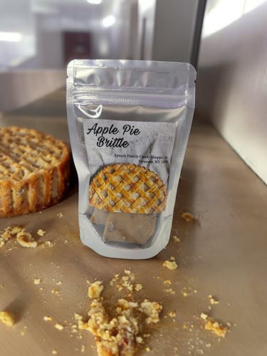 bag of apple pie brittle on a counter with an apple pie