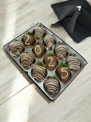 Grad Berries - milk chocolate berries with white chocolate drizzle and number chocolate on four berries in a box on a white wood countertop with graduation cap