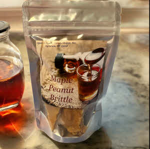 Maple Peanut Brittle Bag on marble counter with jar of maple syrup