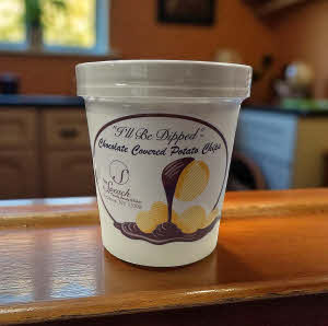 4 oz. container of chocolate covered potato chips on a wooden counter in a kitchen