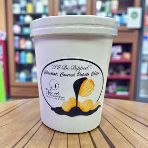 8 ounce container of chocolate covered potato chips on wooden counter in store