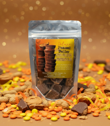 Deluxe Peanut Butter Crunch Brickle bag surrounded by peanuts, broken peanut butter cups, orange and yellow ribbons on a brown background with glitter