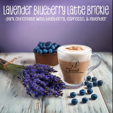 Lavender Blueberry Latter Brickle label - spray of fresh lavender, fresh blueberries and a latte in clear coffee cup on white wooden counter with purple background